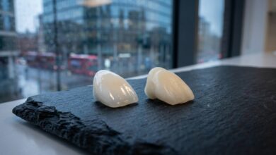 A photorealistic close-up of a high-quality porcelain veneer and a composite veneer on a clean surface, with a blurred background of a modern UK city, symbolizing the cost of cosmetic dentistry.