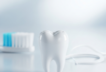 A close-up, highly detailed image of a healthy, pristine white molar tooth, perfectly in focus. In the softly blurred background, a toothbrush head and dental floss are visible, representing oral hygiene and prevention.