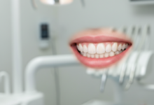 A close-up, photorealistic image of a perfect, radiant smile with healthy, bright, and perfectly aligned teeth. The background is a softly blurred, clean, and modern dental clinic interior.