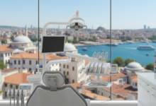 A modern, clean dental clinic interior featuring an empty dental chair and state-of-the-art equipment. Through a large window, a blurred, scenic view of a Turkish coastal city with blue water and architecture is visible in the background, illustrating dental tourism.
