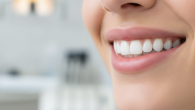A close-up, photorealistic image of a person's radiant, healthy smile with perfectly aligned, bright white teeth. The background is a soft, blurred bokeh of a modern, clean dental clinic interior.