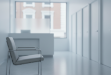 An empty, pristine, and modern dental waiting room, featuring a single, unoccupied gray waiting chair in the foreground. In the blurred background, a reception desk and several closed white doors of treatment rooms are visible, hinting at unavailability. Through a large window, a very subtle, out-of-focus suggestion of British red-brick architecture can be seen outside, emphasizing a UK setting. The scene is quiet, sterile, and conveys a sense of prolonged waiting and inaccessibility.