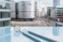 Close-up of modern, sterile dental instruments on a tray, with a softly blurred cityscape of Birmingham, UK, in the background. The image signifies professional dental services and urban healthcare.
