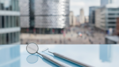 Close-up of modern, sterile dental instruments on a tray, with a softly blurred cityscape of Birmingham, UK, in the background. The image signifies professional dental services and urban healthcare.