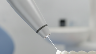 A close-up, photorealistic image of a sophisticated dental laser emitting a focused beam of light onto a tooth or gum, set against a blurred background of a modern dental clinic.